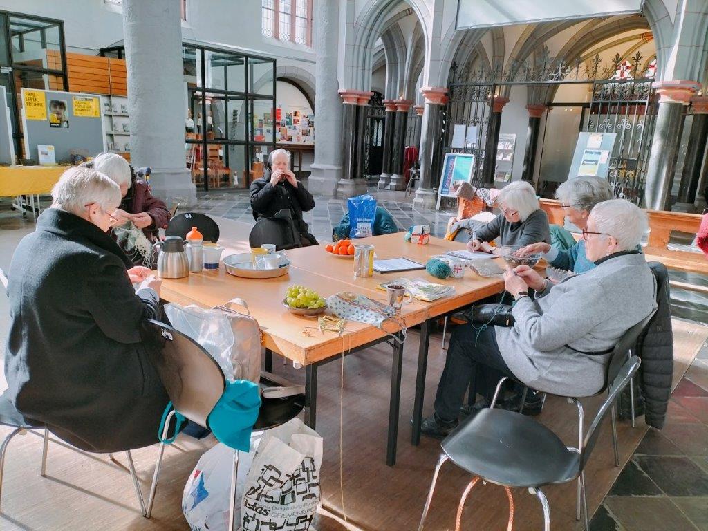 Strickende und Kaffee trinkende Menschen in an einem großen Tisch in der Aachener Citykirche