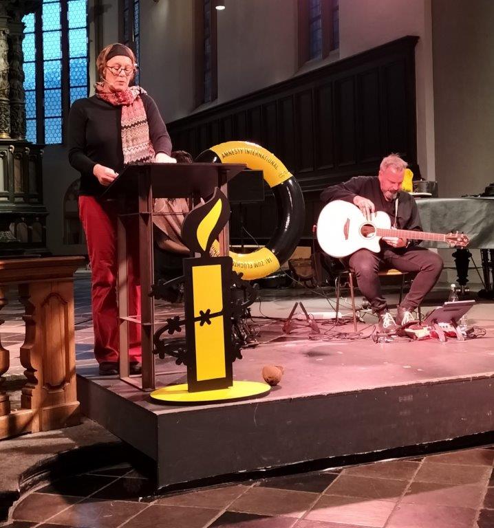 Anette Schmitt liest in der Aachener Citykirche aus "Kleiner Bruder", im Hintergrund Sazan Azodi mit Gitarre.
