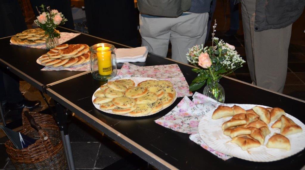 Libanesische Snacks auf Tischen, dazwischen Servietten, Kerzen und Blumen und Glasvasen.