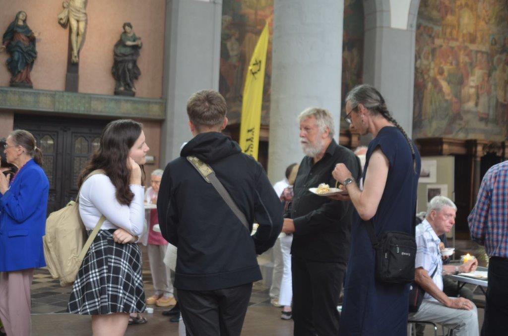 Menschen tauschen sich stehend und sitzend beim Essen aus.