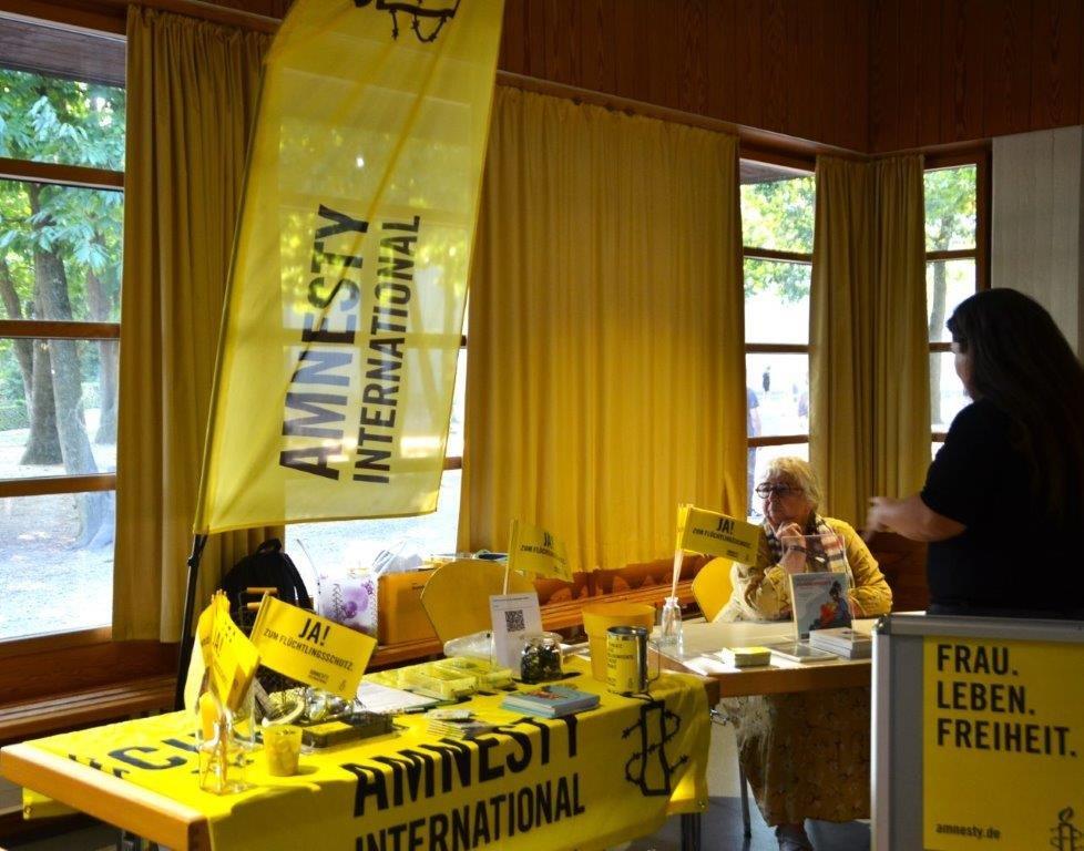 Amnesty-Infostand in einem Klassenraum an zwei Schultischen. Material zu Iran und Flüchtlingsschutz ist zu sehen.