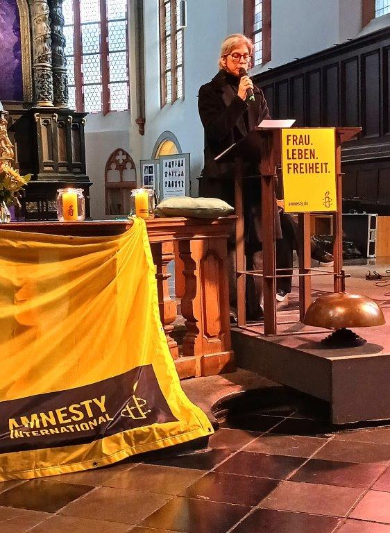 Im Altarraum der Citykirche wird ein Text vorgetragen. An dem Pult ist ein gelbes Amnestyplakat mit der Aufschrift "Frau. Leben. Freiheit."