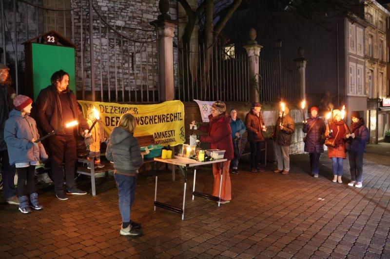 Menschen mit Fackeln bei der Mahnwache am Vorabend des Tags der Menschenrechte vor der Eupener Nikolauskirche.