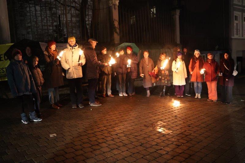 Menschen mit Fackeln bei der Mahnwache am Vorabend des Tags der Menschenrechte vor der Eupener Nikolauskirche.