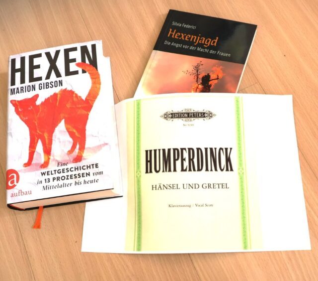Tischplatte mit Büchern über Hexen und Hexenprozesse sowie einem Notenbuch zu Hänsel und Gretel.