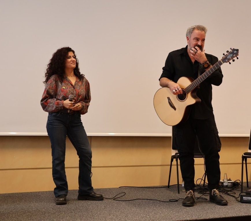 Eine Sängerin und ein Gittarist stehen auf einer Bühne.