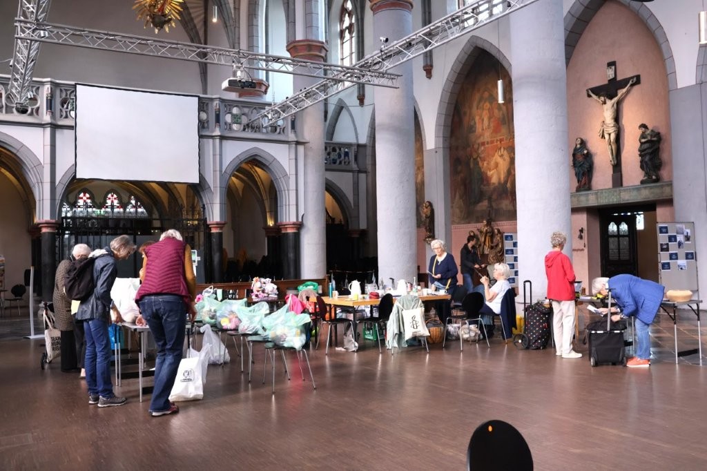 Totale vom Wollsammeltag in der Aachner Citykirche: Es sind Personen, Tische, Stühle und viele Tüten mit gesammelter Wolle zu sehen.